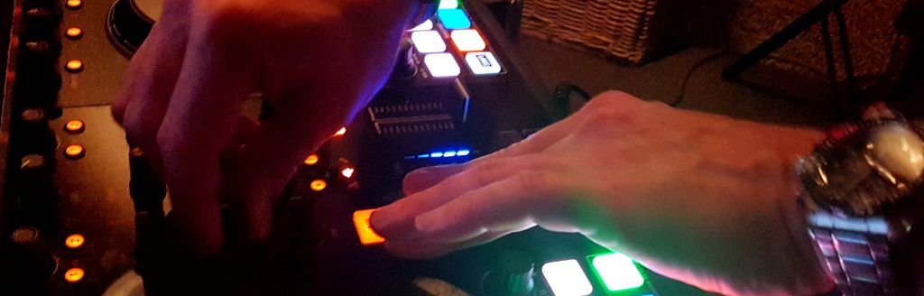 DJ Arjan met beide handen op de verlichte Traktor-controller achter de booth tijdens een bruiloftsfeest